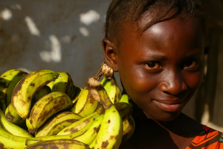 Niña africana con frutas en el hombro